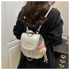 Détail du sac à dos argenté métallisé avec chaîne décorative et charme en peluche