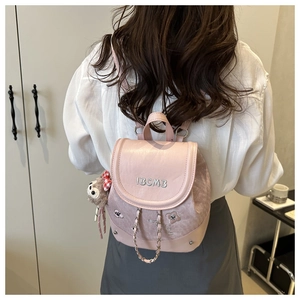 Detailed view of pink mini backpack with IBCMB embroidery and cute monkey plush charm