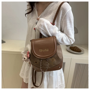 Détail d'un sac à dos vintage marron avec broderie IBCMB, motifs ours et breloque en peluche