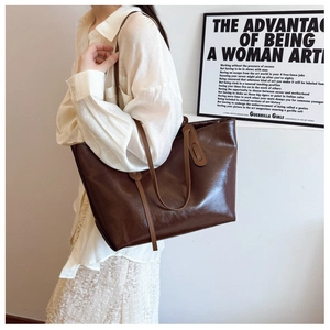 Detail of a large vintage brown faux leather tote bag with slim shoulder straps and handle