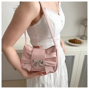 Pink ribbon shoulder bag detail with metallic bow buckle on a soft pleated leather surface
