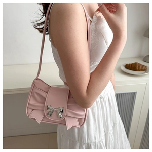 Detailed view of pink bow baguette bag with silver metal buckle on a model