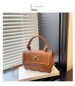 Détail d'un sac marron avec nœud doré et bordure inférieure ondulée élégante