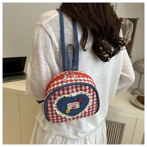 Detail of red quilted mini backpack with denim heart patch and lace trim details