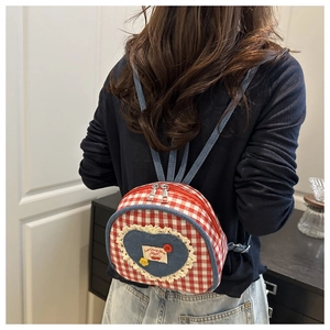 Close-up of mini plaid backpack showing red heart lace and cherry embroidery detail