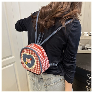 Detail of mini plaid backpack featuring denim heart patch and elegant lace trim
