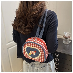 Detail of mini quilted backpack with lace heart, cherry badge and red plaid fabric