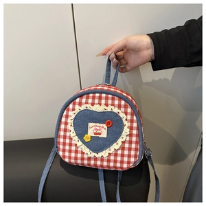 Detail of red checkered mini backpack with lace heart patch and sweet cherry label