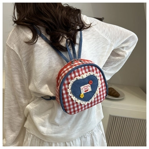 Detail of red plaid backpack with heart denim patch and lace trim embroidery