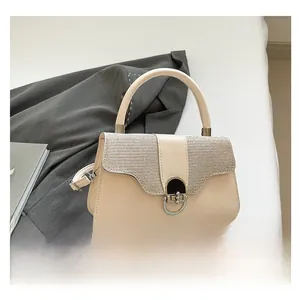 Detail of cream crossbody bag with shimmering sequin flap and round metal lock