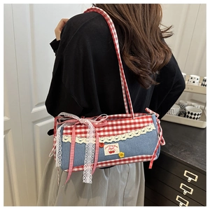 Detail of blue denim shoulder bag with red gingham trim and a large lace bow accent