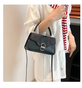 Detail of black glitter handbag featuring silver oval lock and dual-texture design