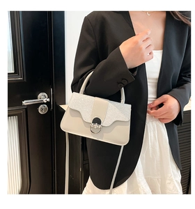 Detail of cream leather crossbody bag with glitter patchwork and round metal buckle