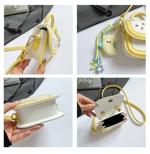 Detail of yellow cherry bag featuring moon plush charm and colorful fringe accessory