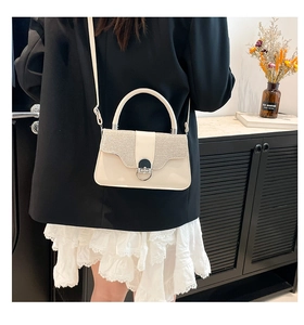 Detail showing the cream white mini square bag with silver sequins and metal lock buckle