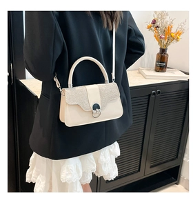 Detail of minimalist cream crossbody bag with silver glitter flap and metallic lock clasp