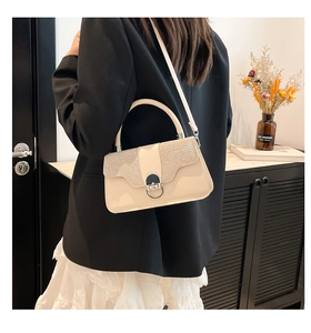 Detail of cream crossbody bag featuring texture contrast and metal ring clasp hardware