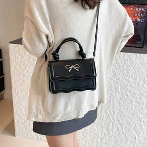 Sac bandoulière en cuir noir avec nœud doré et rabat ondulé pour femme