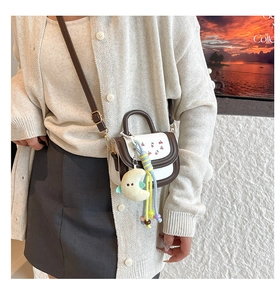 Detail of mini cherry print handbag with plush moon charm and colorful bead strap