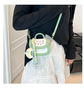 Detailed view of mini green cherry print crossbody bag with cute yellow moon pendant