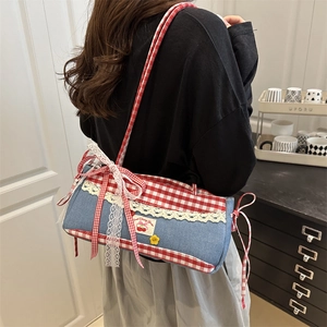 Sac sous le bras à carreaux avec broderie cerise et dentelle porté par un mannequin