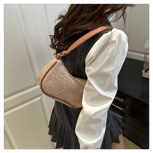 Sac demi-lune en paille avec bandoulière en cuir marron porté par un mannequin en intérieur