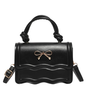 Minimalist black shoulder bag with gold bow clasp and wave-edge flap design