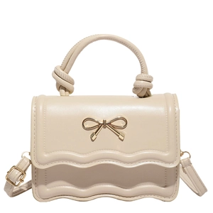 Creamy white crossbody bag with golden bow and scalloped flap shown in a front view