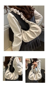 Detailed close-up of a white pleated crescent shoulder bag with ruffle strap design