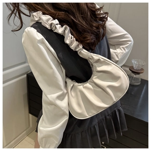 Detail of cream pleated shoulder bag with ruffled strap showing texture and elegant style