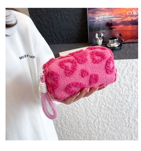 Detalle de bolsa de maquillaje de felpa rosa con patrones de corazones y asa suave