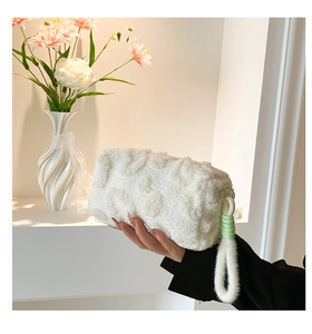Detalle de neceser de felpa blanca con textura de leopardo y asa con adorno verde
