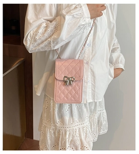 Detail of light pink quilted phone bag with silver bow buckle and chain strap