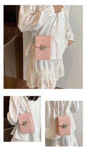 Detail view of pink quilted mini crossbody phone bag with silver bow buckle and chain strap