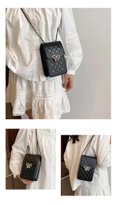 Detail of black quilted leather phone bag featuring silver bow clasp and chain strap