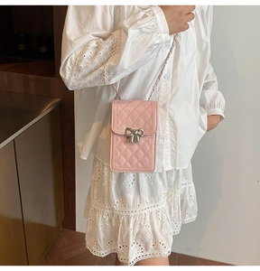 Detailed shot of pink quilted crossbody bag with silver bow accent and chain strap