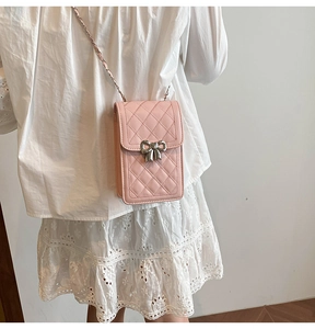 Detail of pink quilted phone bag with silver bow accent worn as a crossbody on a lace dress