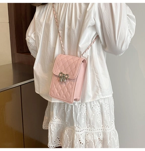 Detail of pink quilted mobile phone bag with silver bow buckle and leather chain strap