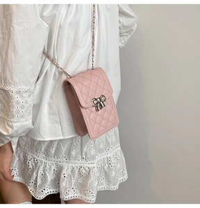 Detail of pink quilted phone bag with silver bow buckle and woven chain strap