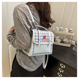 Close-up of light blue plaid backpack featuring red apple embroidery and flip cover