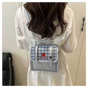 Detailed view of light blue checkered mini crossbody bag with red apple embroidery