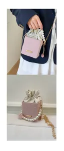 Pink woven bucket bag featuring pearl beaded handle and golden metal chain detail