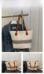 Detailed view of a beige woven tote bag with brown handles and lace embroidery detail