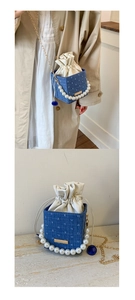 Detail of blue denim bucket bag with pearl handle, gold chain, and drawstring closure