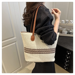 Detail of a large cream woven tote bag with coffee floral trim and brown straps