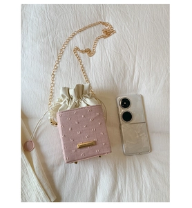 Pink bucket bag with pearl chain detail, drawstring closure, and metal corners