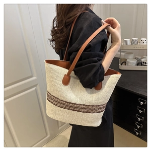 Close-up of contrast woven straw tote bag with brown leather straps and cutout details