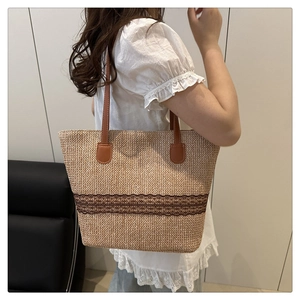Detail of summer straw woven tote bag featuring brown faux leather handles and lace trim