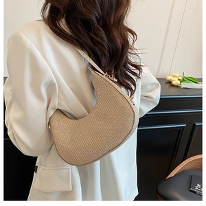 Chic champagne crescent shoulder bag with shimmering finish worn by model in stylish setting