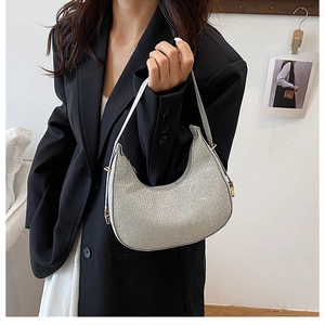 Close-up of a silver glitter crescent bag with gold hardware on a black suit model